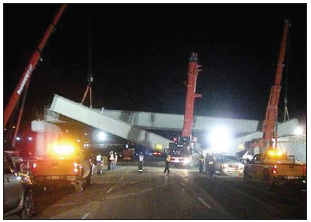 A bridge whose beams have collapsed during construction at night.